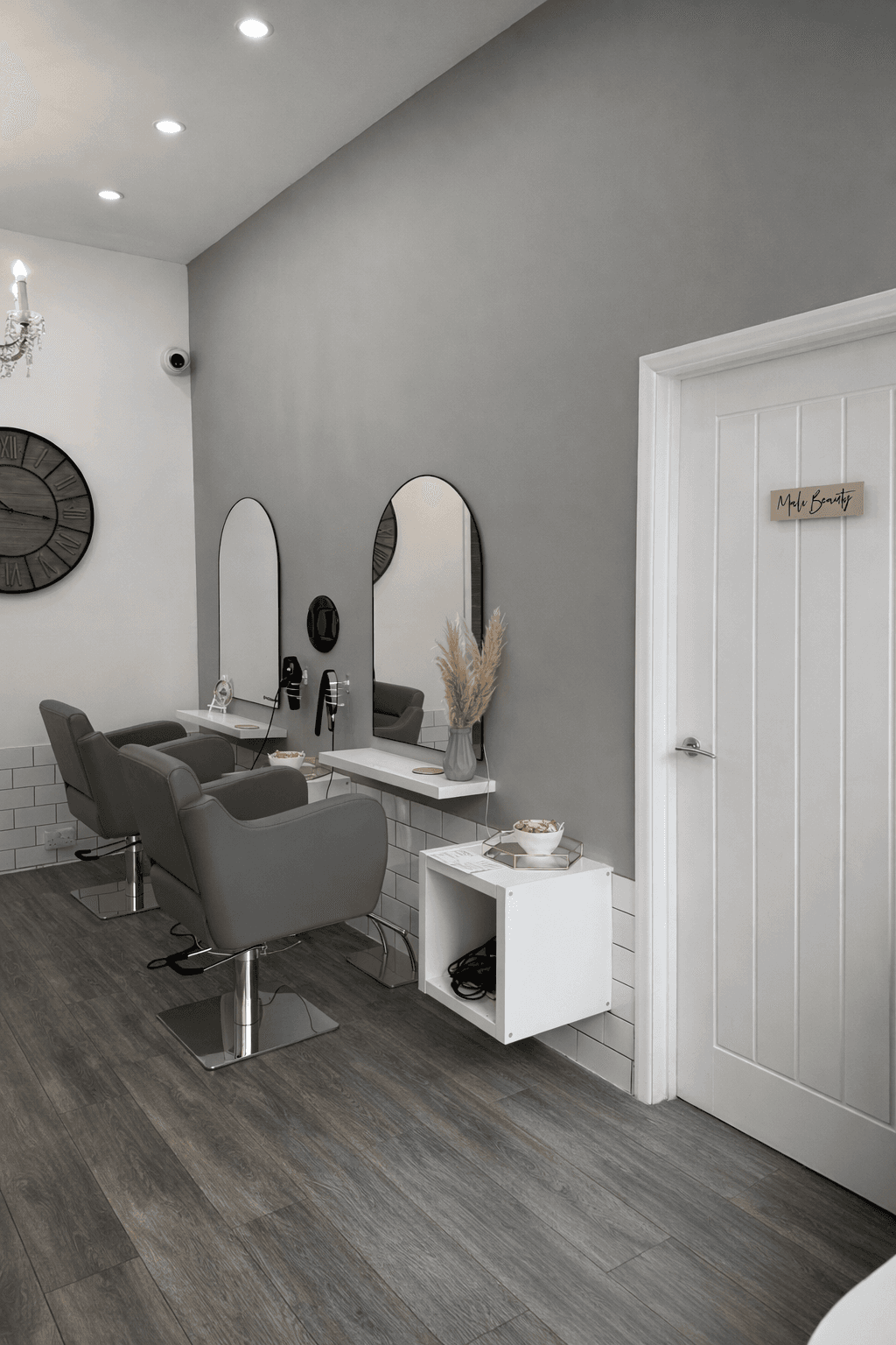 Clean, modern salon interior with grey styling chairs, wall mirrors, and a clean minimalist treatment space