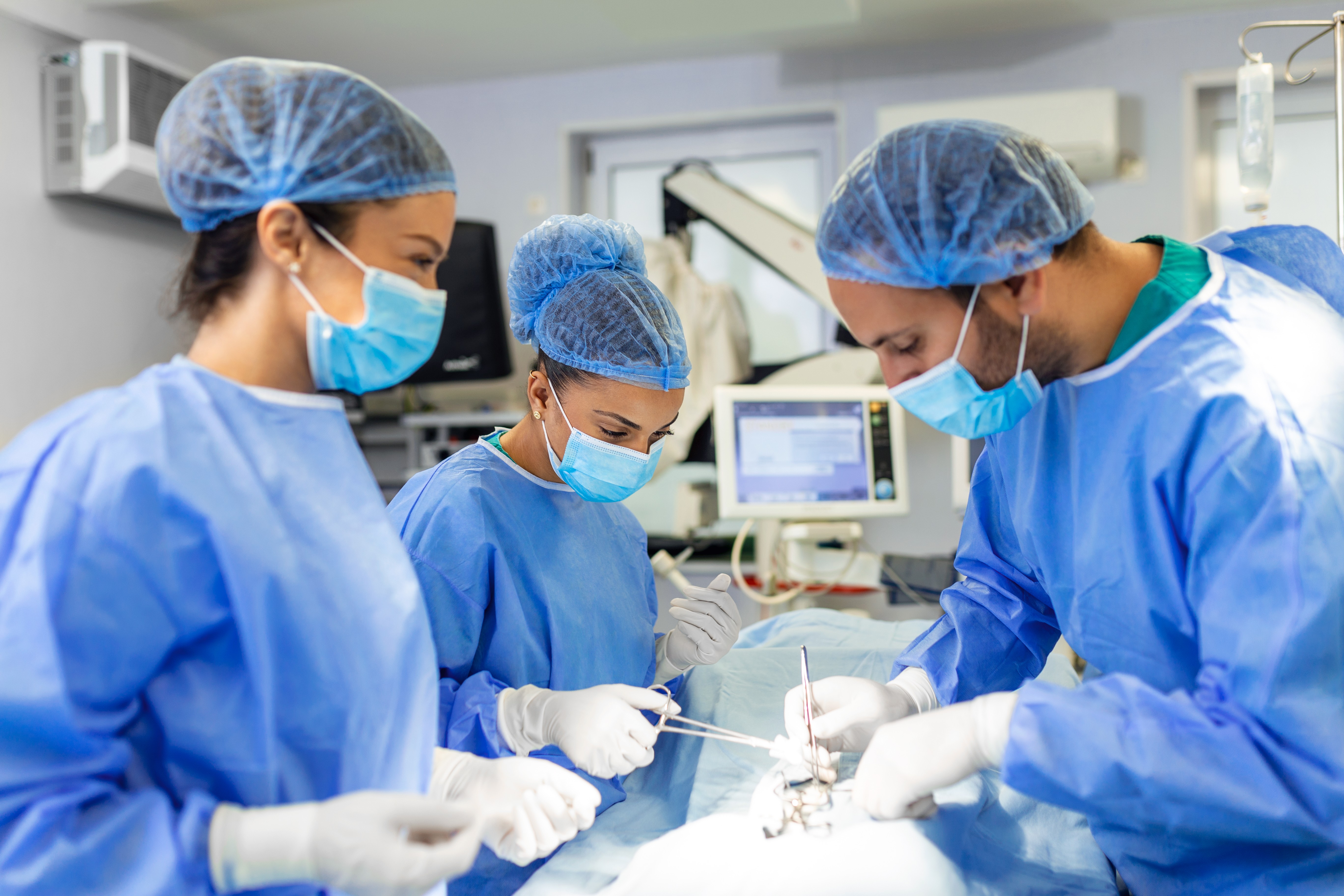 A doctor in a white coat discusses with two women in a medical office, highlighting a professional healthcare setting.