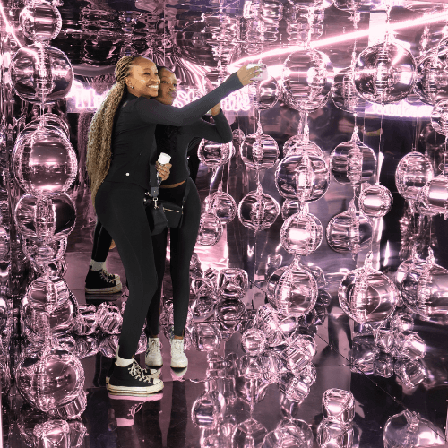 Guests taking selfies inside Baluma’s Mirror Cube photo booth at a luxury Johannesburg event.