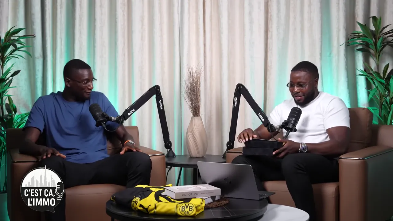 Serhou Guirassy et Salimou Sidibé face à face dans le studio de C’est ça, l’immo pendant la séquence de remise des clés à Dubaï, Salimou tenant des coffrets noirs