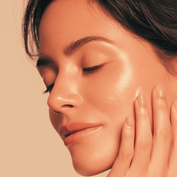 Close up of woman with dark hair with eyes closed, hand on cheek with beautiful glowing skin - Sylfirm X at Live Supreme