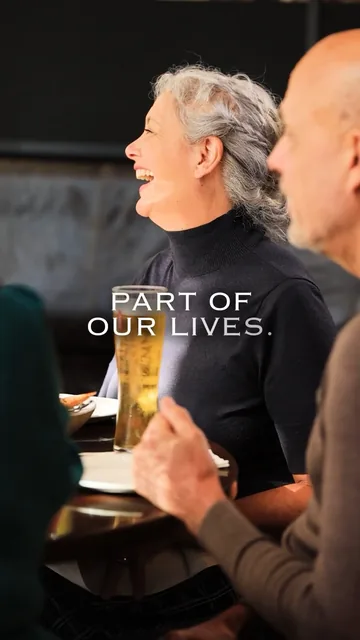 Two regulars laughing at a table, under the words “Part of our lives”