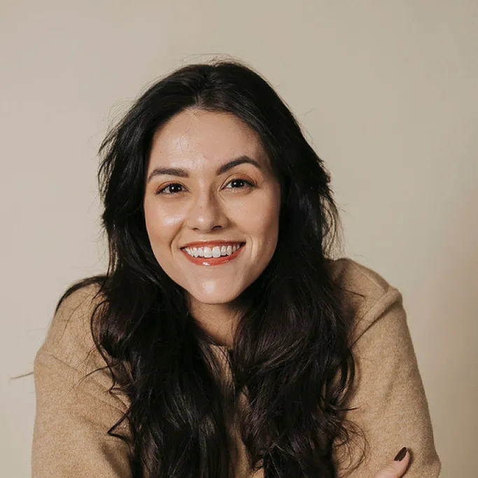 Uma pessoa sorridente, vestindo um suéter verde claro. Atendimento da BuilderSession