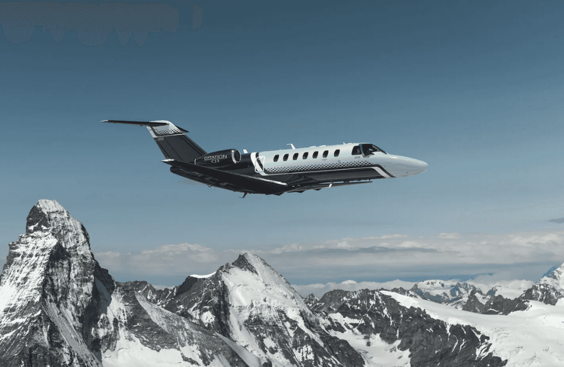 Cessna Citation CJ3 private jet flying over snowy mountain peaks