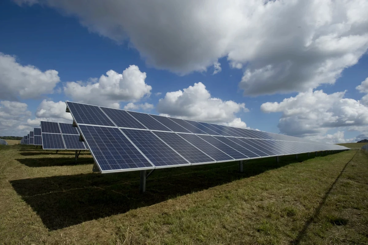 Solar panels array under a blue sky with clouds.