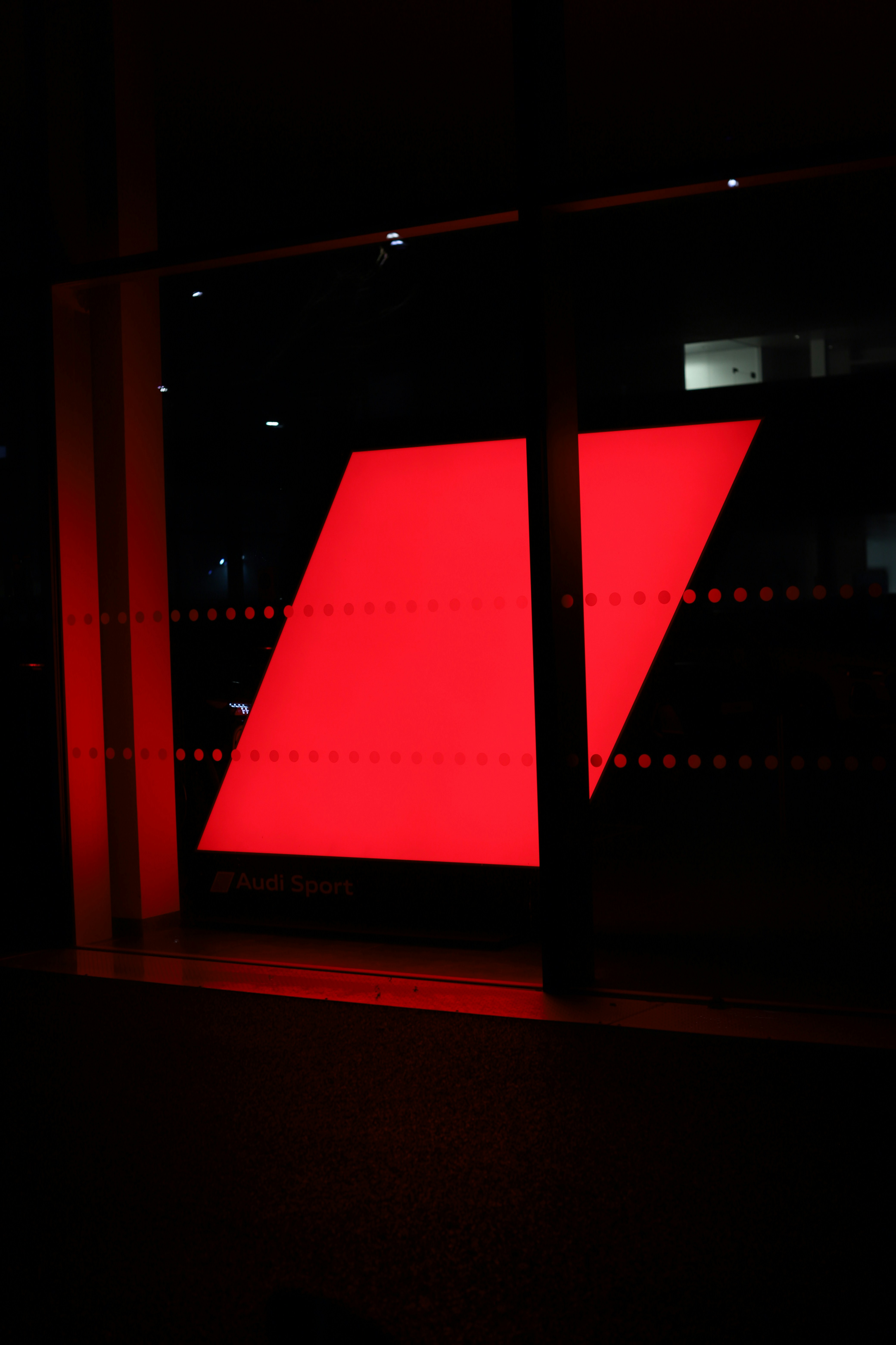 A large red geometric shape illuminates a dark background.