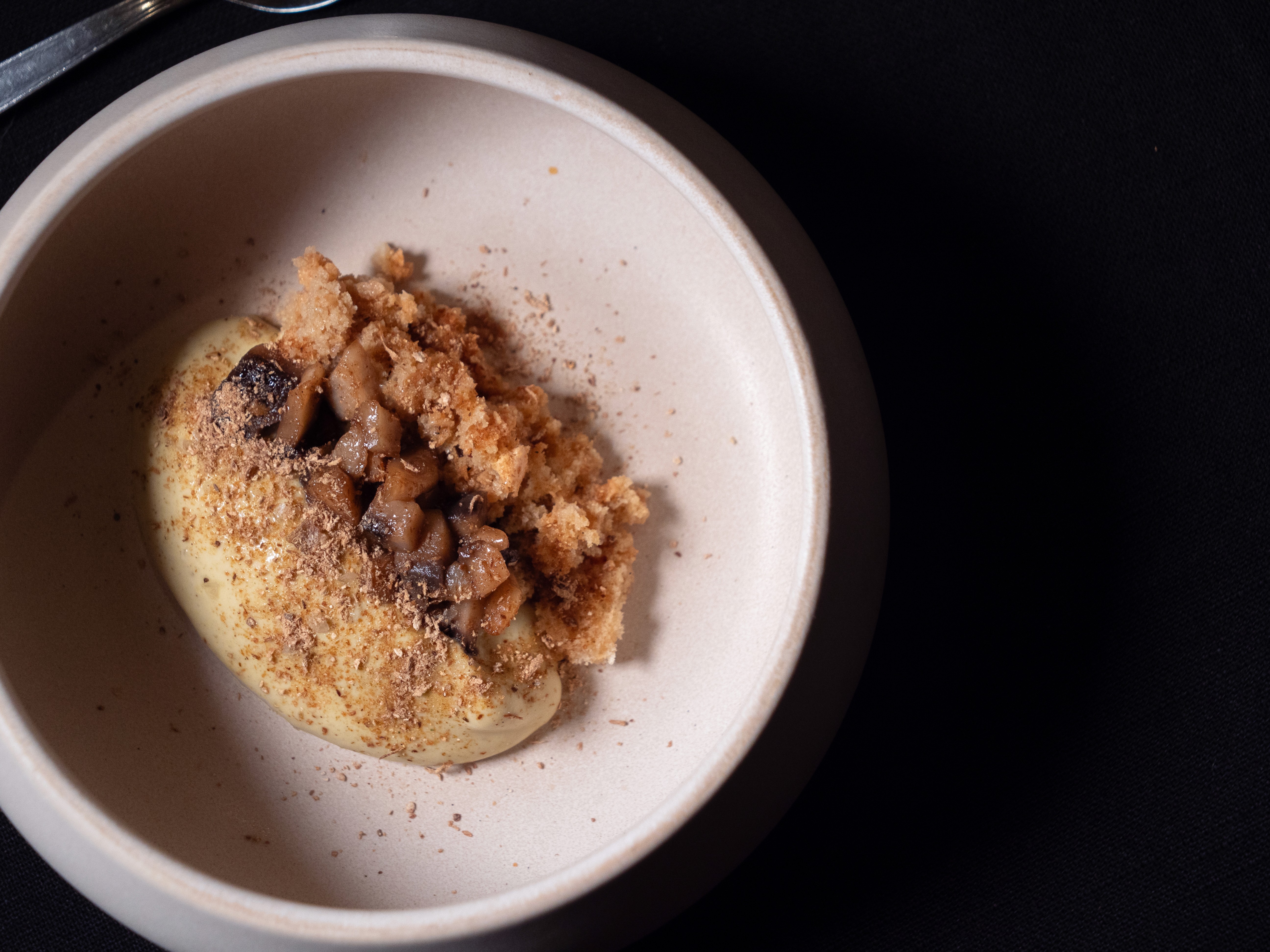 Plate with a seared salmon fillet topped with green herb garnish and sauce, served on a white dish placed on a dark green marble table beside a white candlestick.