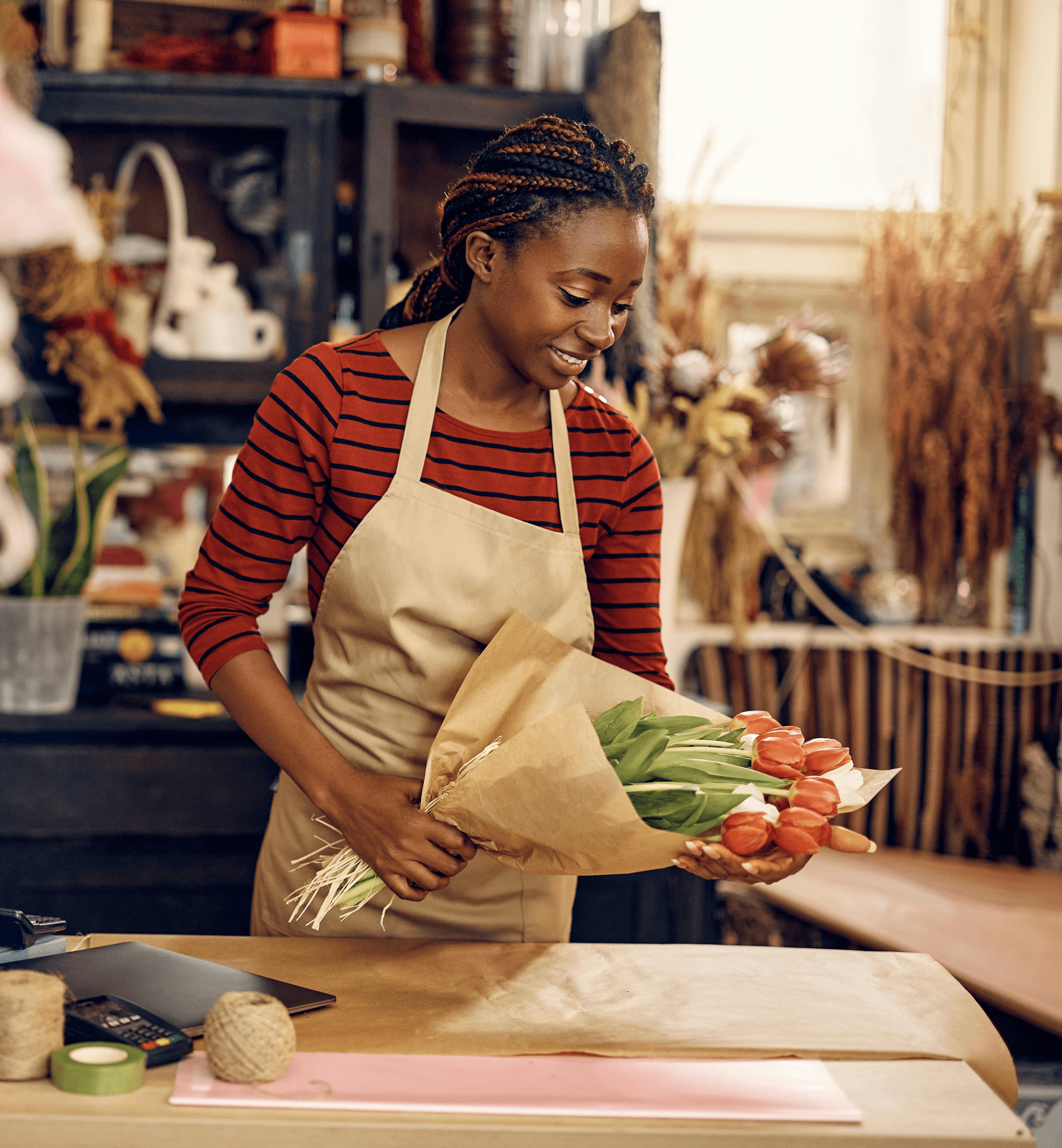 A florist arranges flowers at a workstation surrounded by colorful bouquets in a cozy shop.