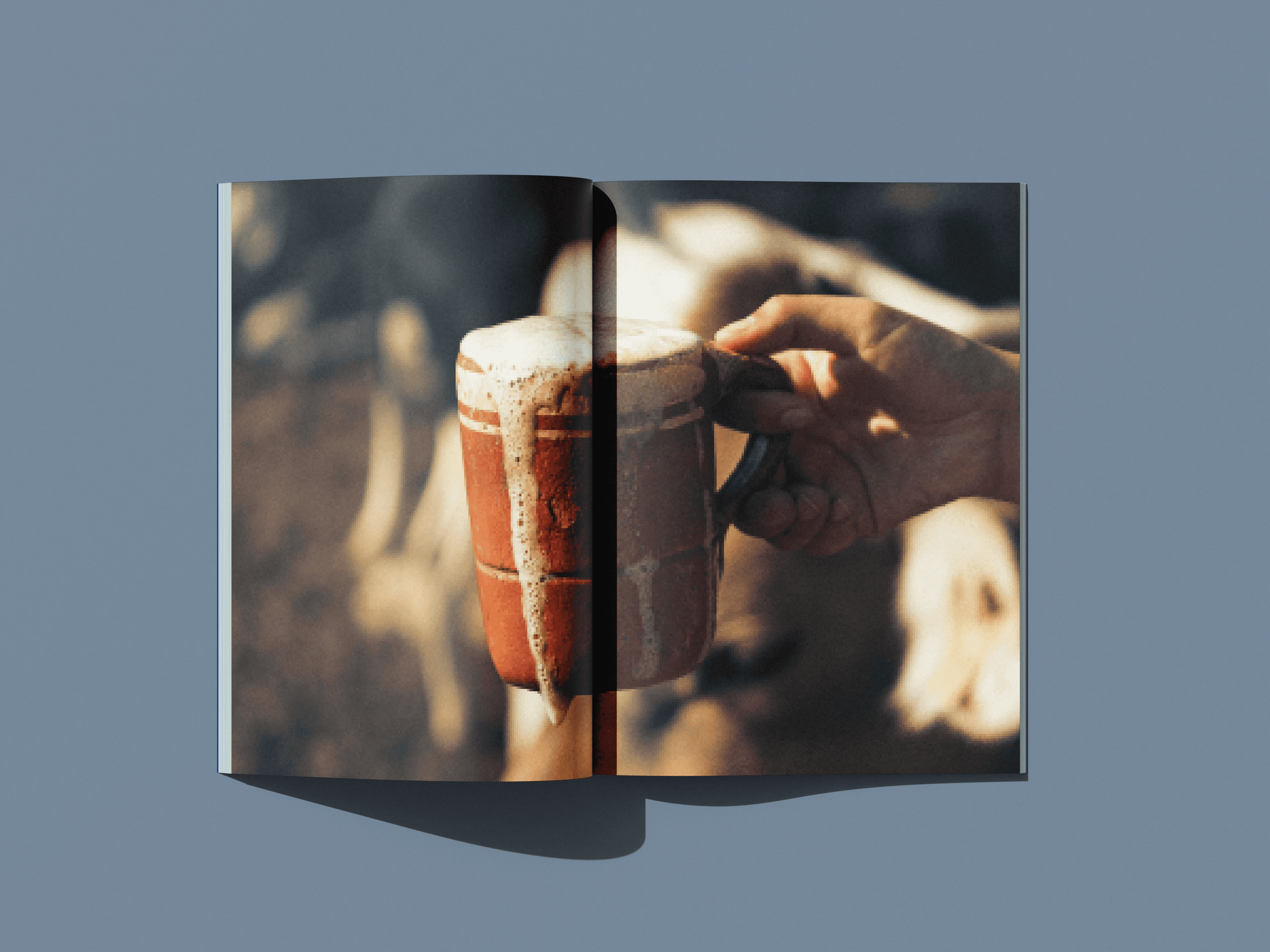 Full-bleed brochure spread showing a hand holding a wooden mug of foamy milk.