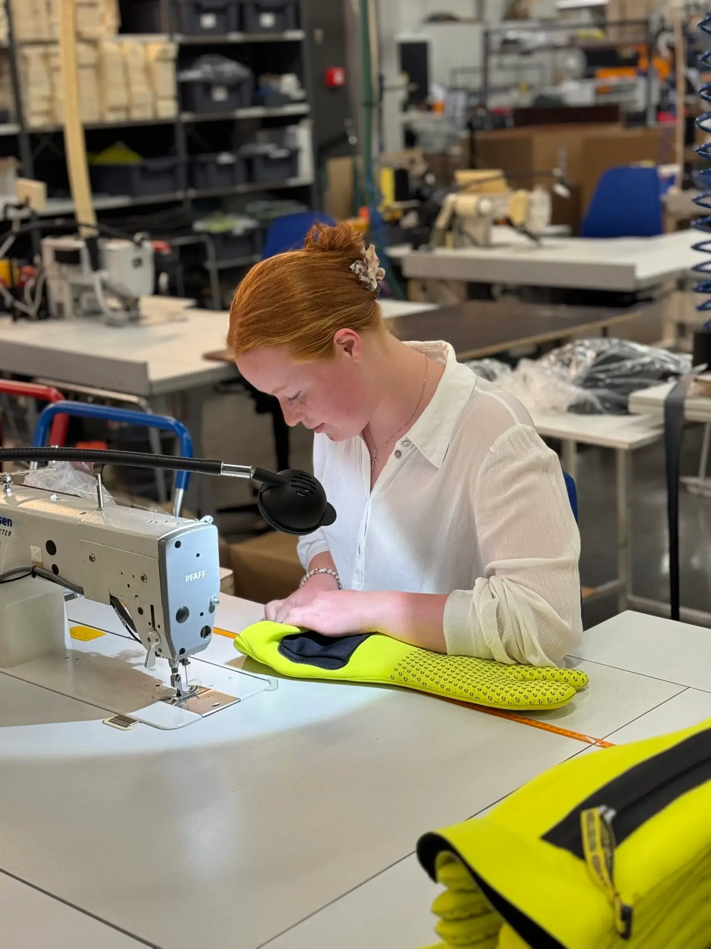 Lærling i industrisøm syr verneklær ved industrisymaskin
