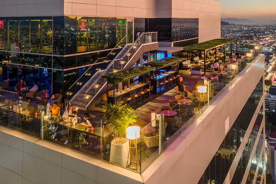 Bar en la terraza del Hotel Riu Guadalajara con cancelería premium y vista nocturna de la ciudad