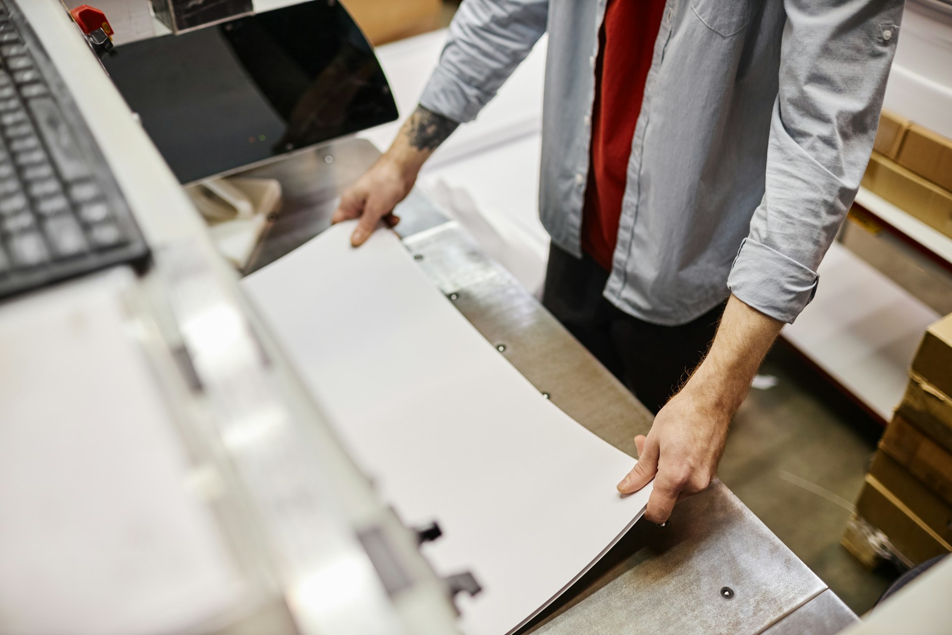 A man in a grey and red shirt operating a large format printer