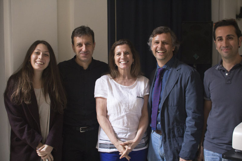 A photo of a group of people standing near a white wall.
