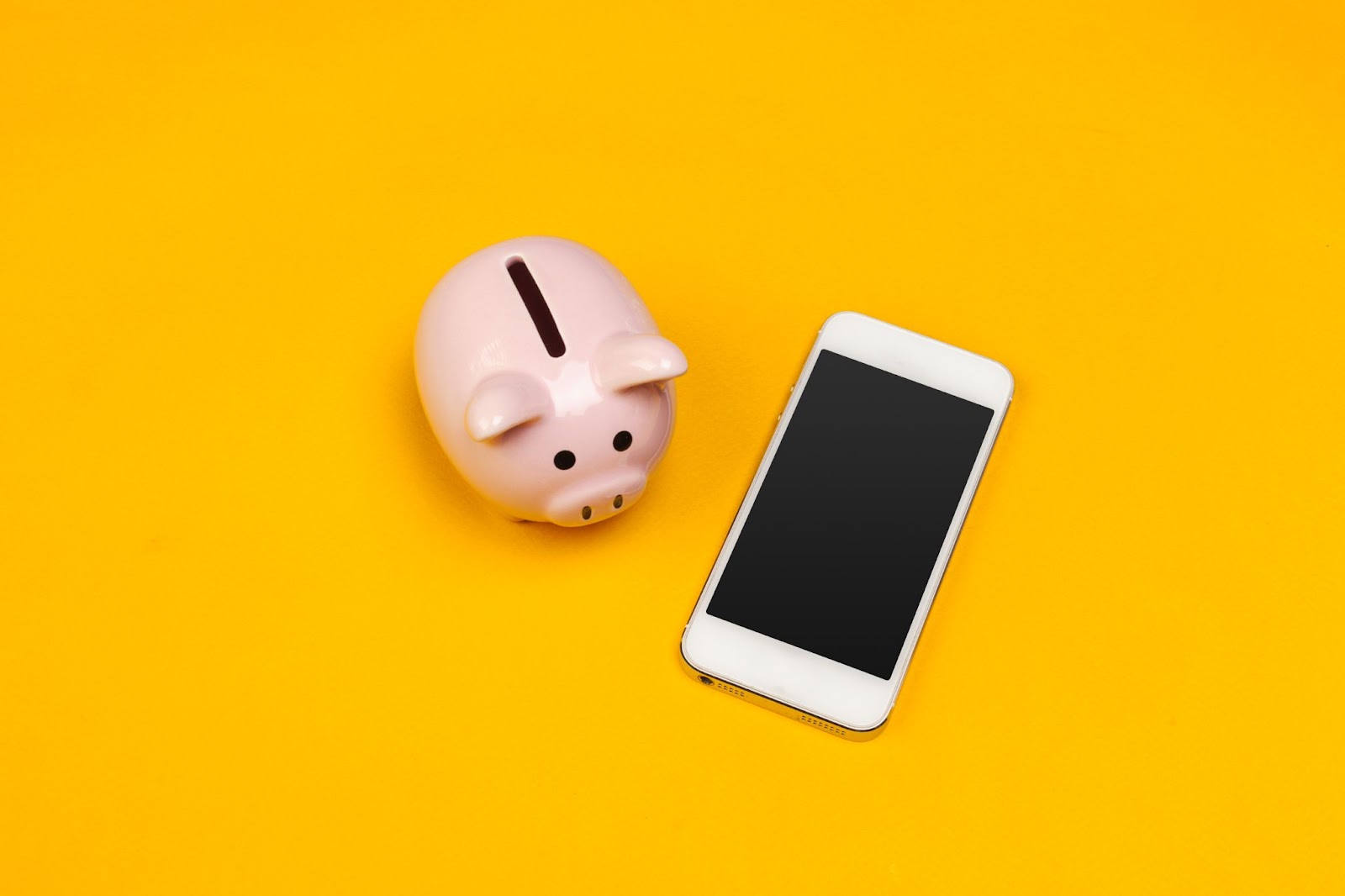 Phone next to a piggy bank. 