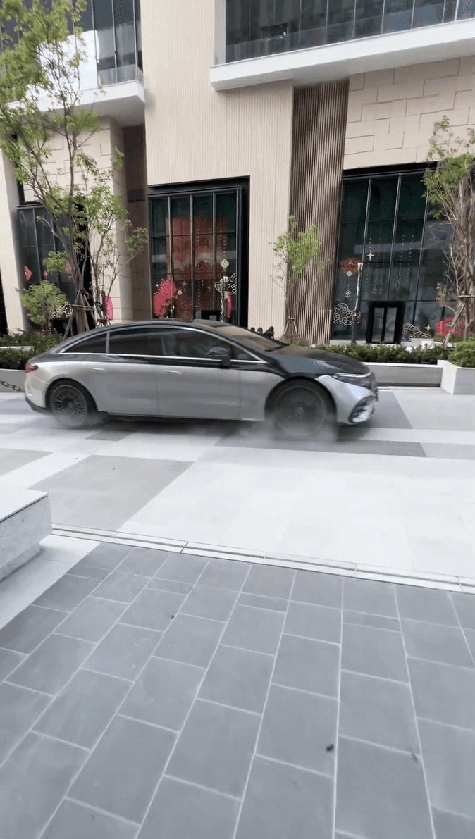 A silver Mercedes-Benz drives smoothly across a modern tiled pedestrian plaza