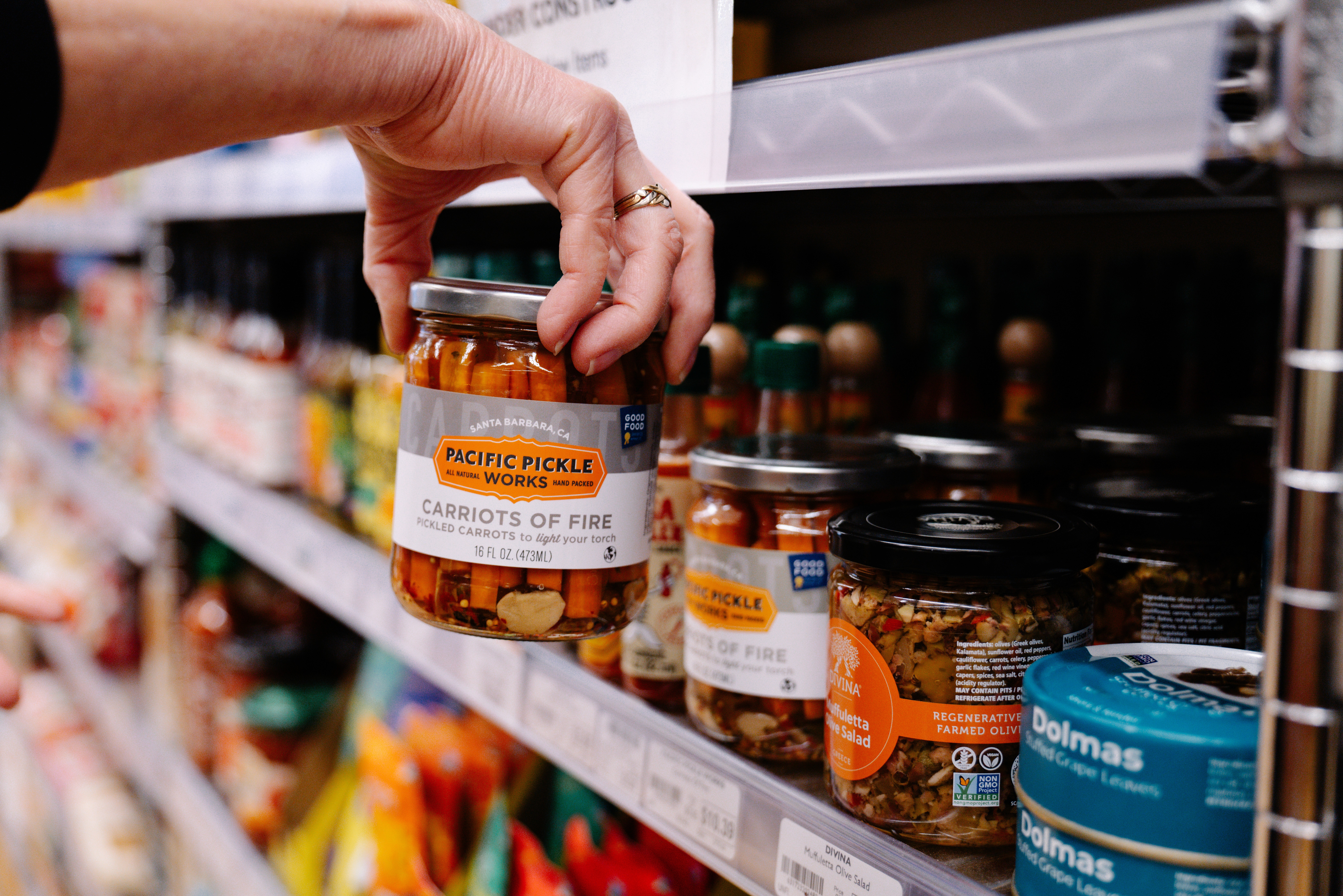 A customer at a checkout counter is interacting with a cashier while placing items in a bag.