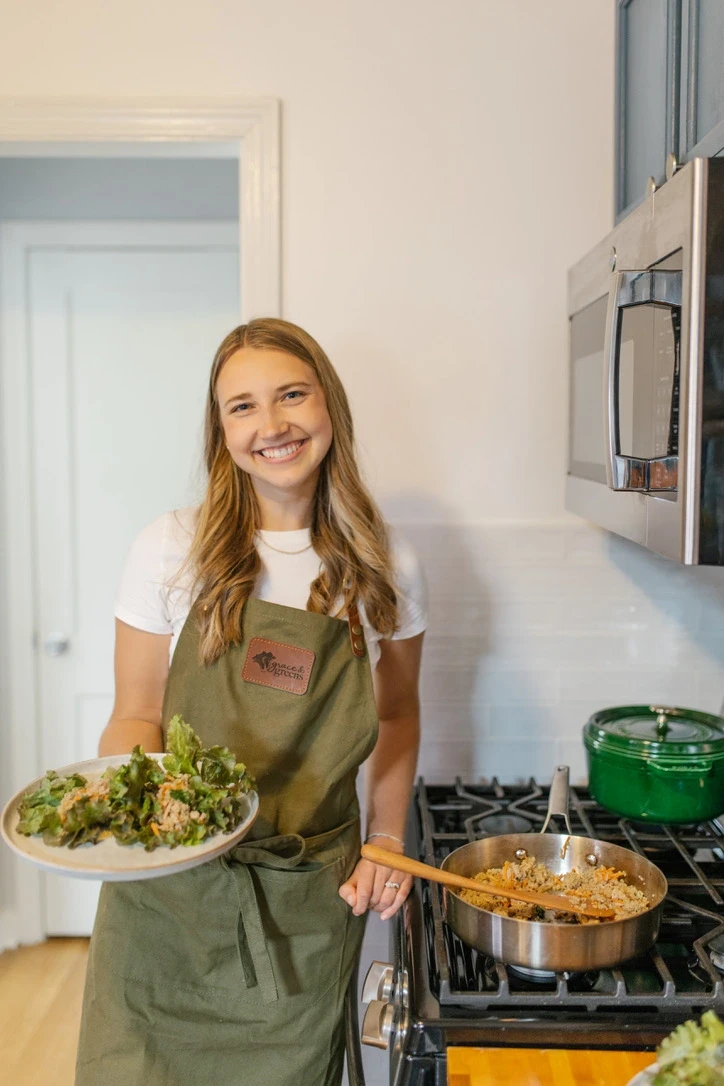 blonde woman cooking a delicious gluten-free dairy-free recipe of lettuce wraps by the stove in a green apron