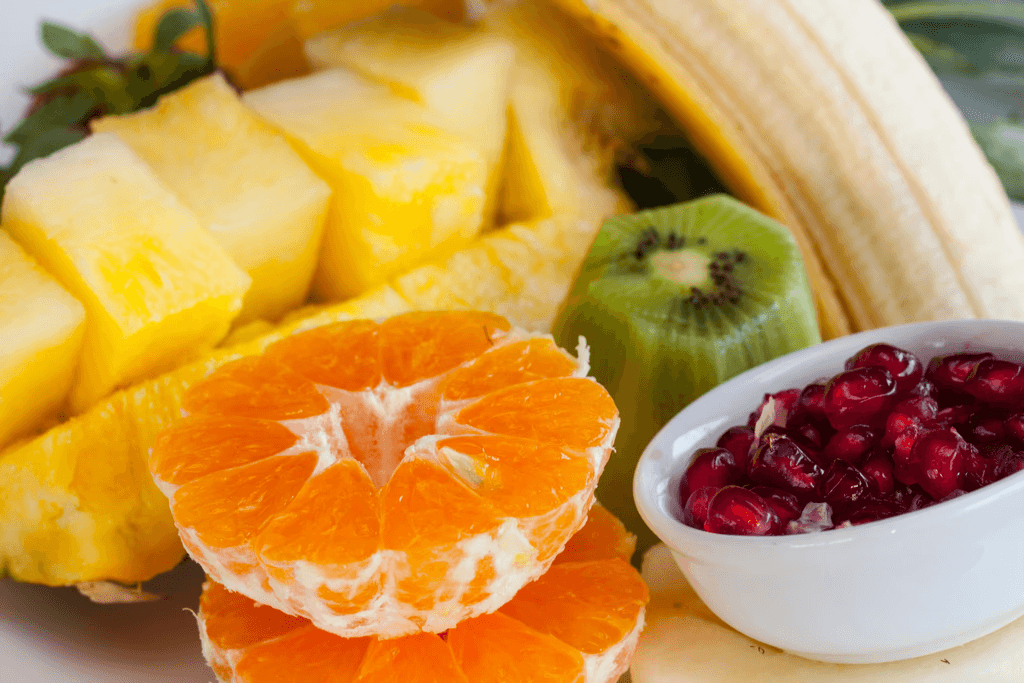 A colorful assortment of fresh fruits including pineapple, banana, orange slices, green apple, and pomegranate.