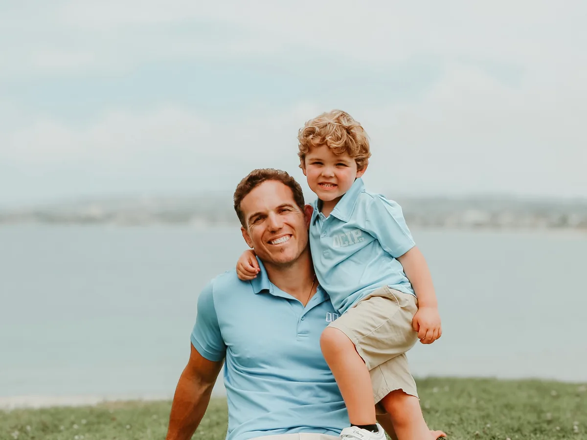 Tyler Watkins with his son Tyler Watkins with his son, both wearing light blue OCIP shirts.