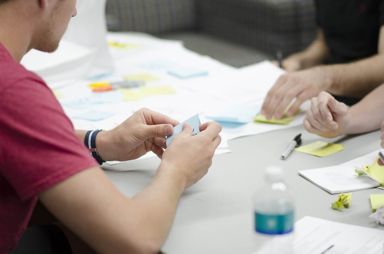 A creative team of three with a man holding a sticky note