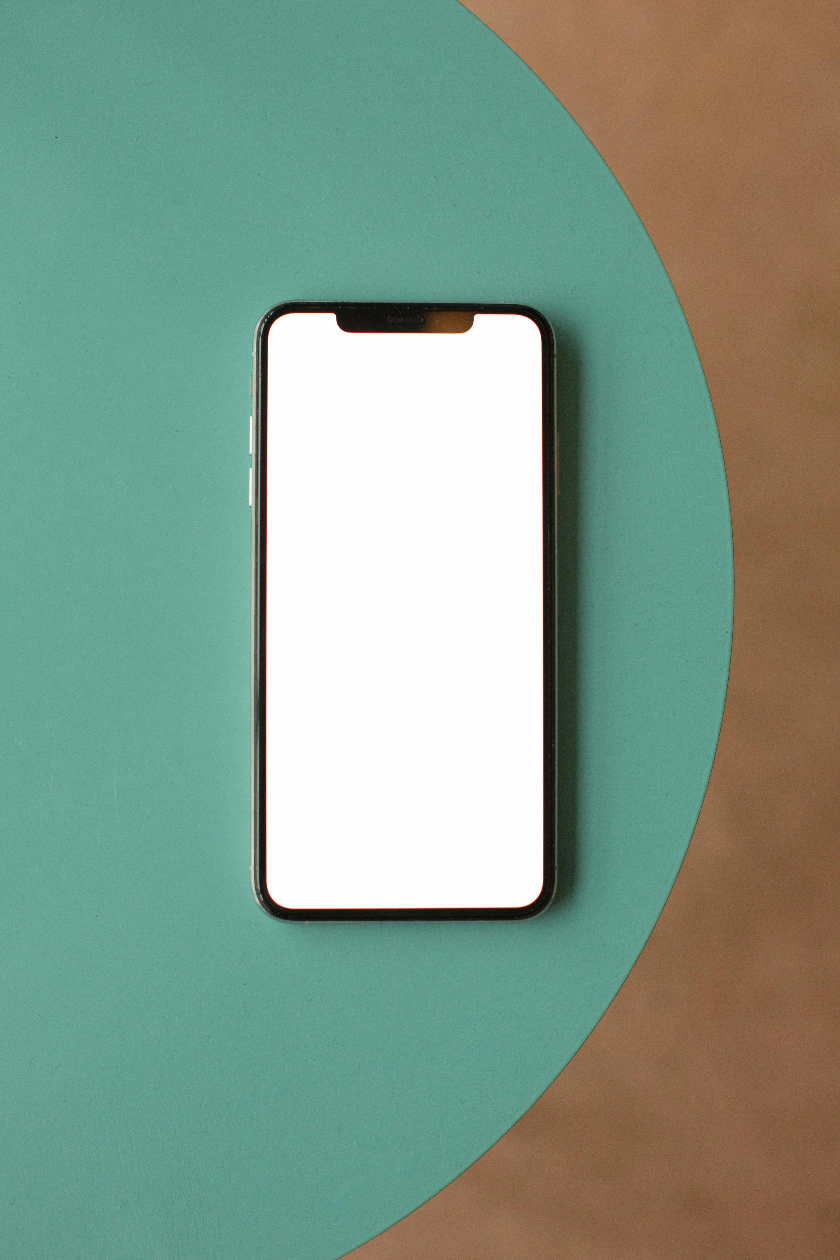 Smiling young woman with long hair standing against a dark green background, holding a finger to her chin.