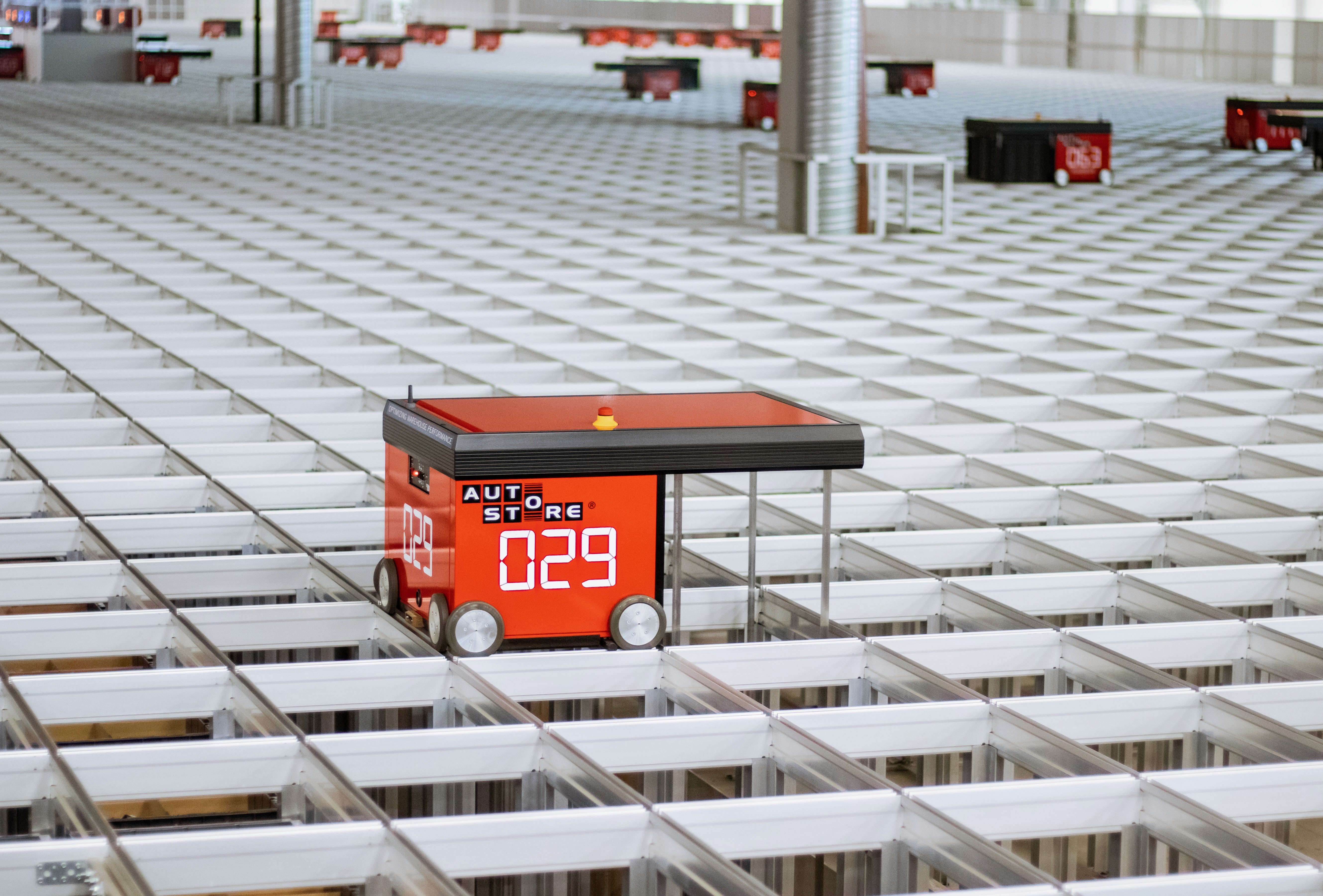En röd lagerrobot som arbetar i ett automatiserat lager för varor, numrerad 029.
