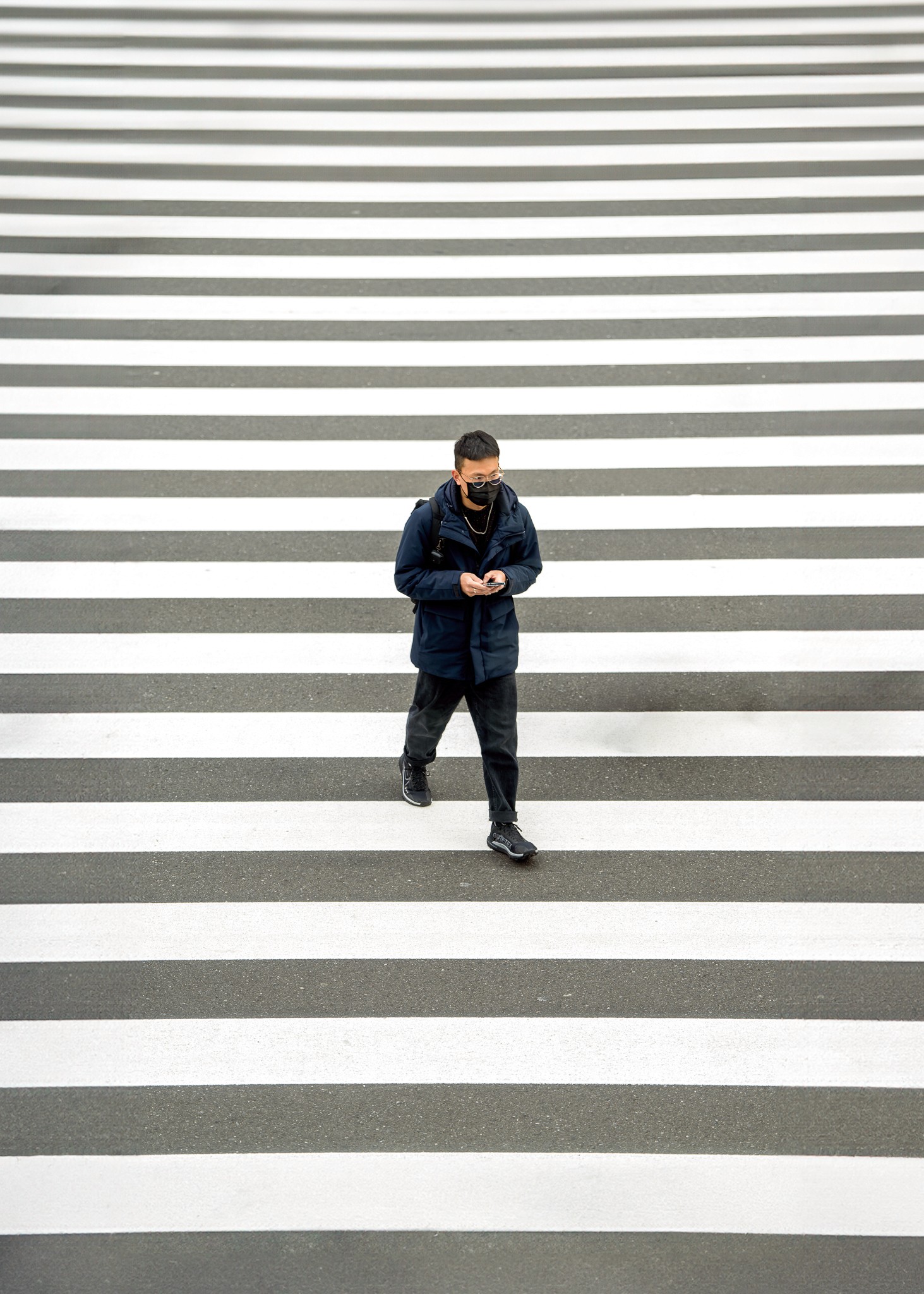 Close-up portrait of a person wearing a gray insulated hooded jacket with the hood up, showing their face framed by the hood against a light background.