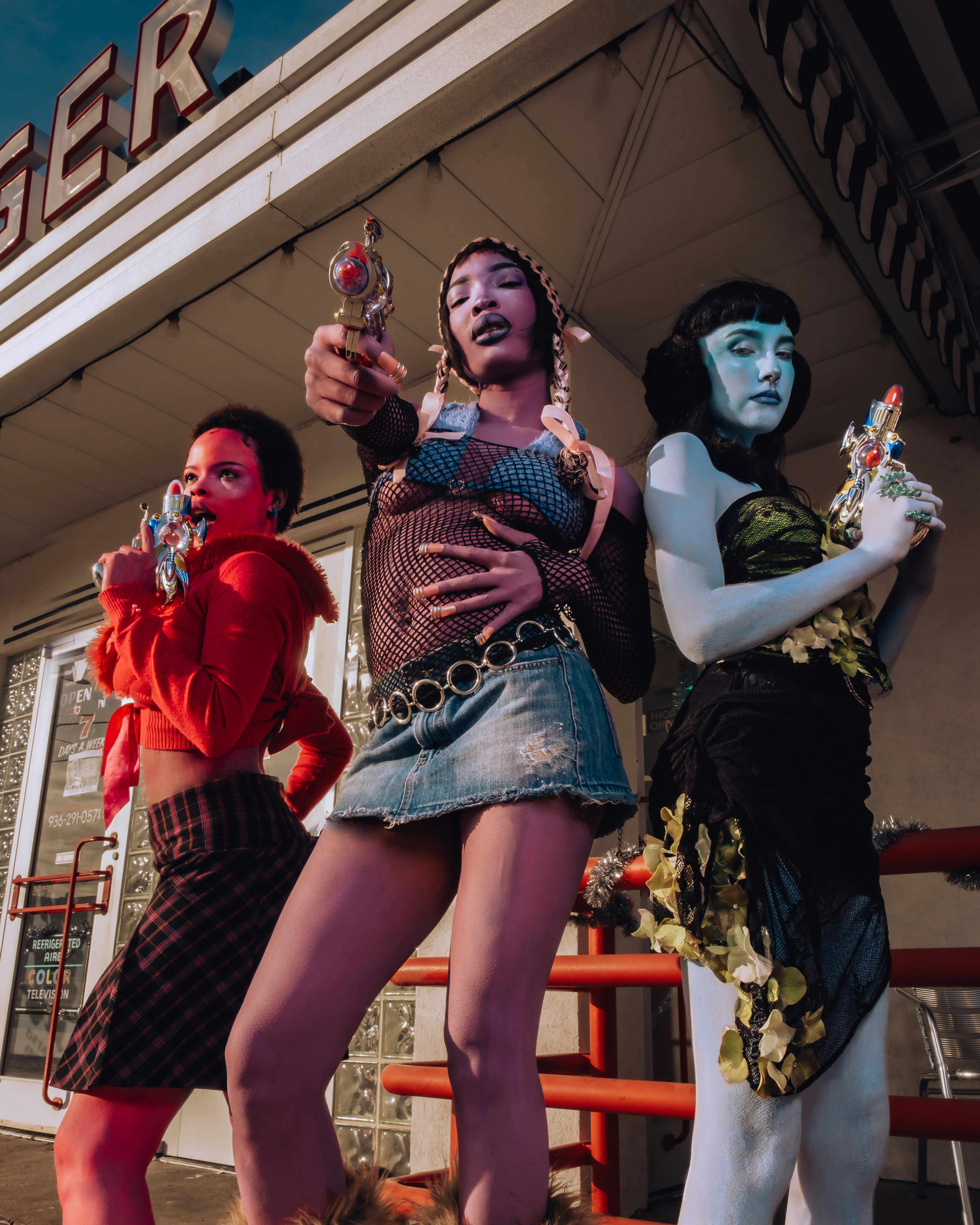 Three stylish people holding toy guns outside