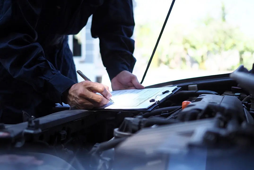 Person documenting vehicle repair details during an estimate process.