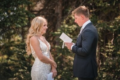 Tucker reads from a folded sheet of paper as Clemmie smiles in the forest clearing.