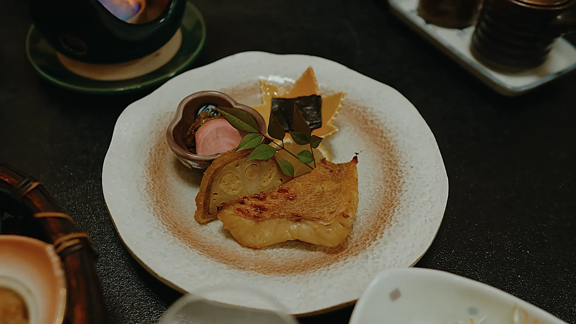 A plated course at Kurokawa Onsen, a grilled item with a garnish
