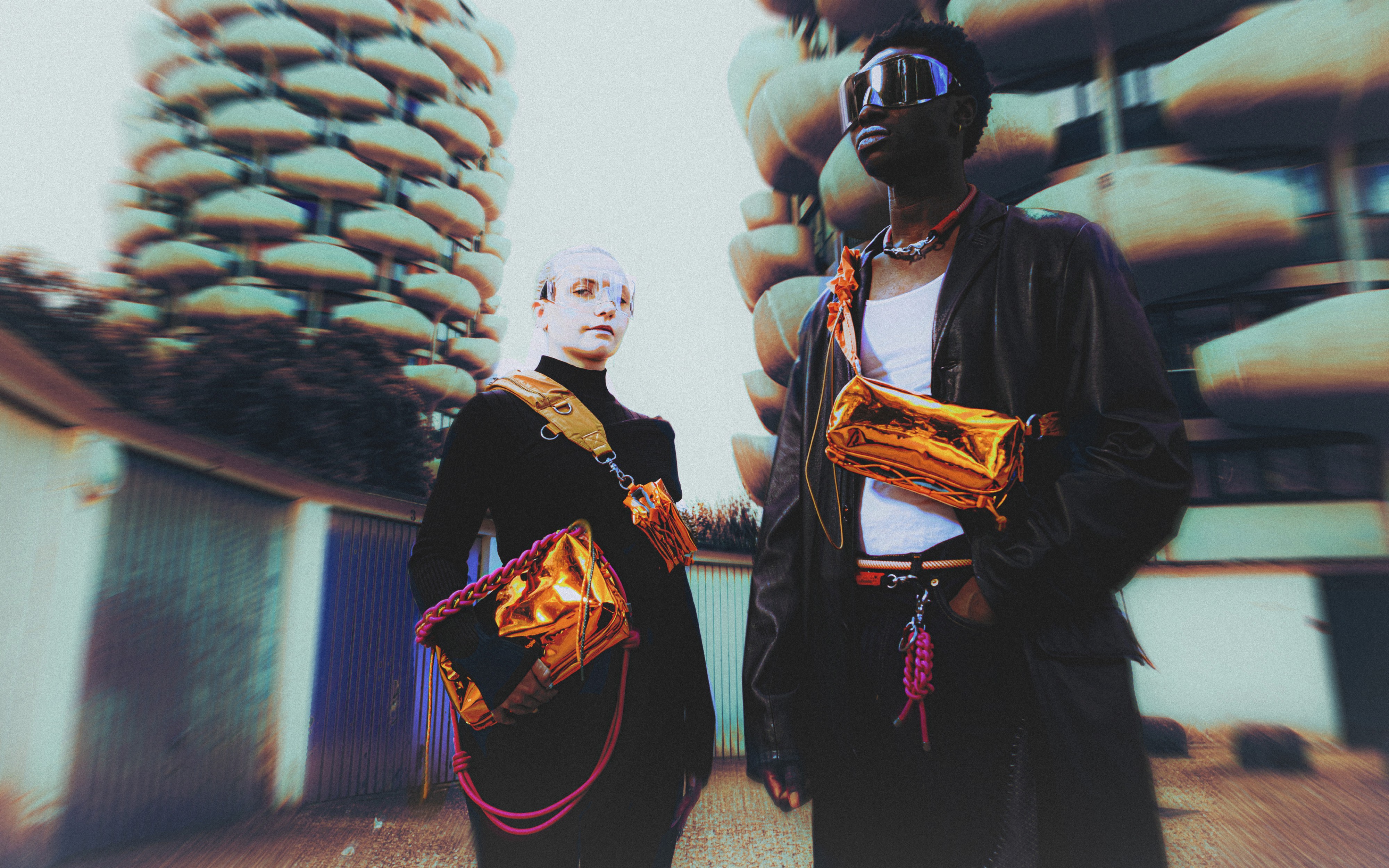 Un homme et une femme posent avec des sacs orange fluo devant les chous de creteil, immeubles futuristes