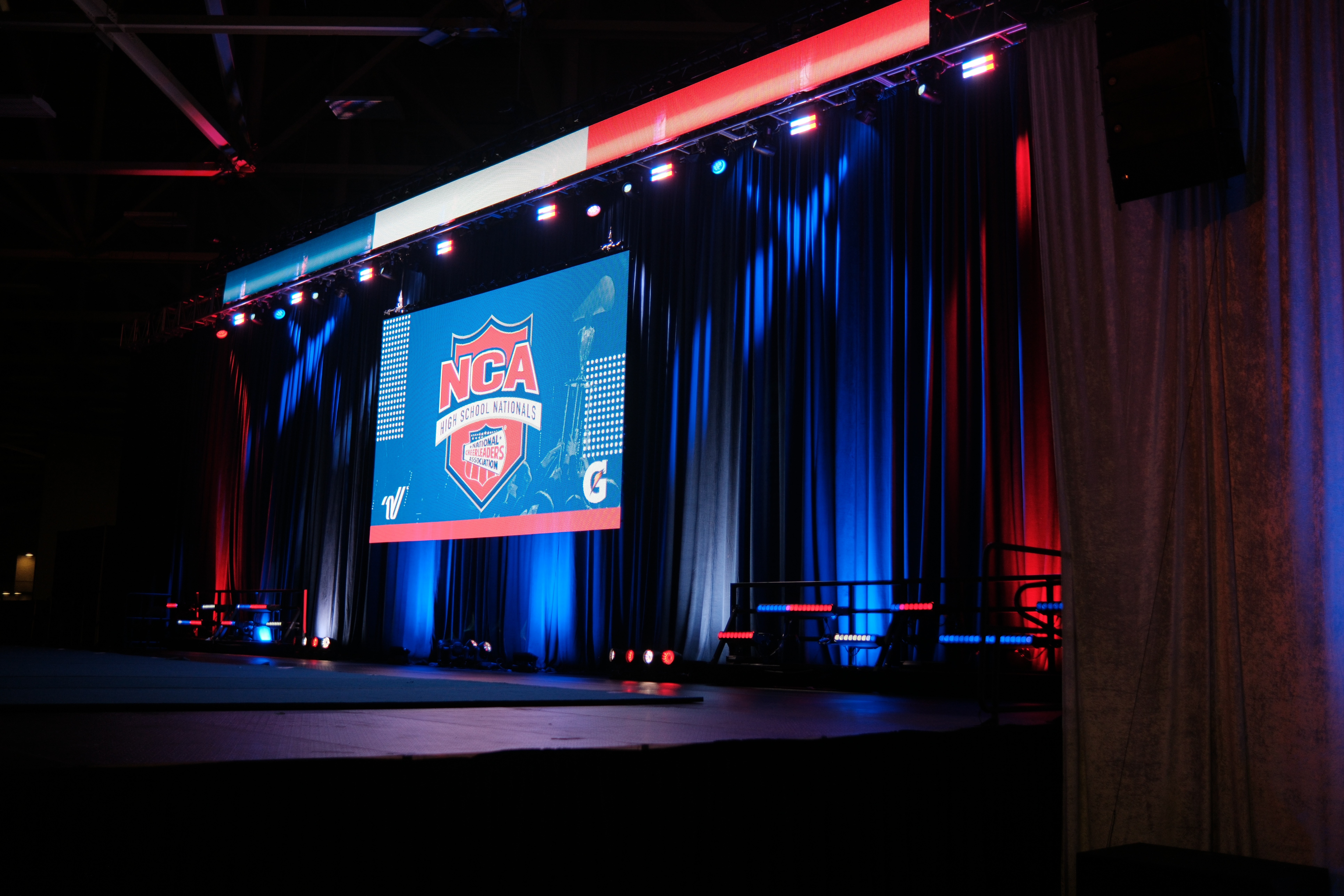 Angled view of the NCA video wall and blue drapes at NCA High School Cheerleading Nationals, Dallas — event staging by UpLight Technologies