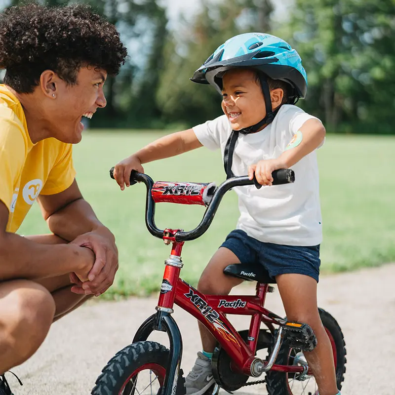 a guide helping a child ride a bike