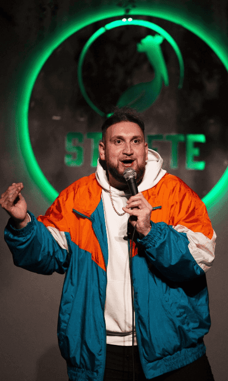Comedian in orange in blue jacket at St Pete Standup