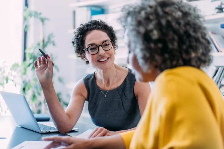 Financial consultant and client discussing debt relief and wealth building strategies with a laptop and documents on desk.