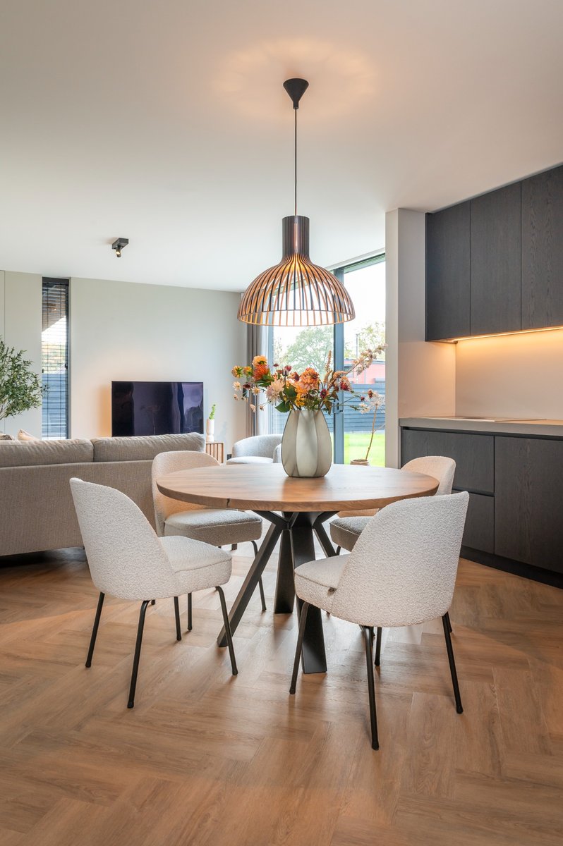 ronde eettafel lichte stoelen en zwarte keuken