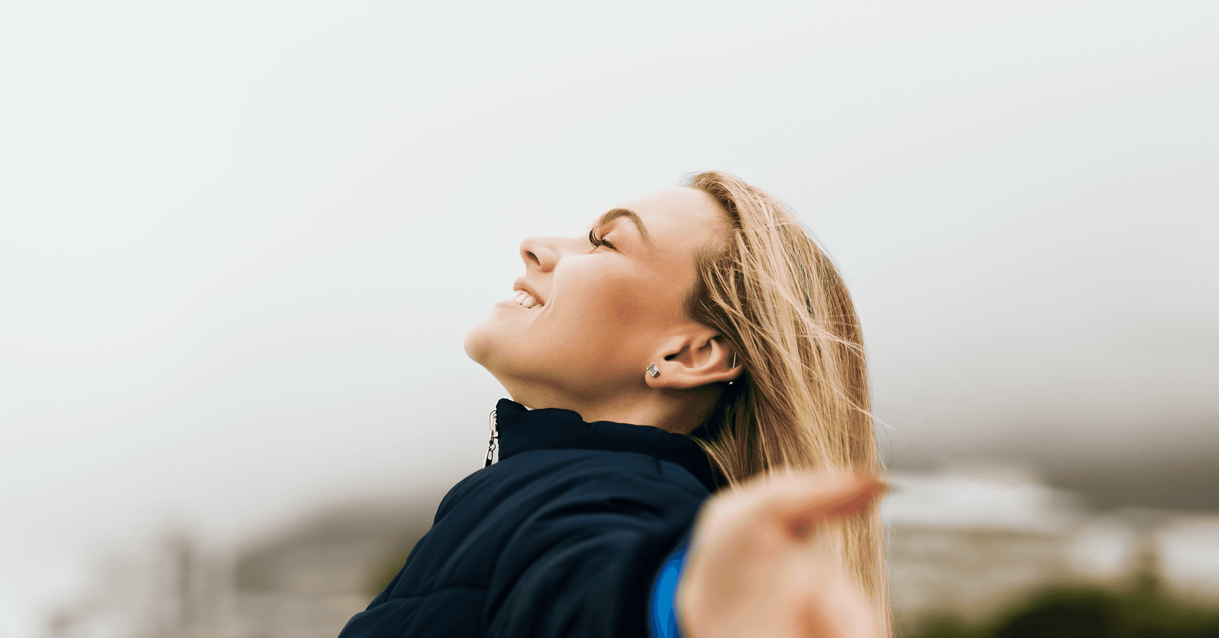 En kvinna står med öppna armar och njuter av den friska brisen.