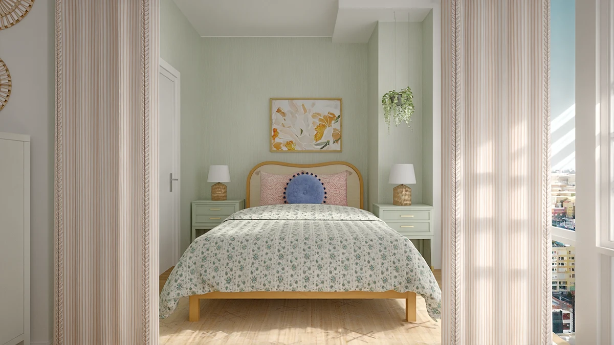 A cozy bedroom with sage green walls, a light wood bed with floral bedding, and matching green nightstands, viewed through a curtained doorway.