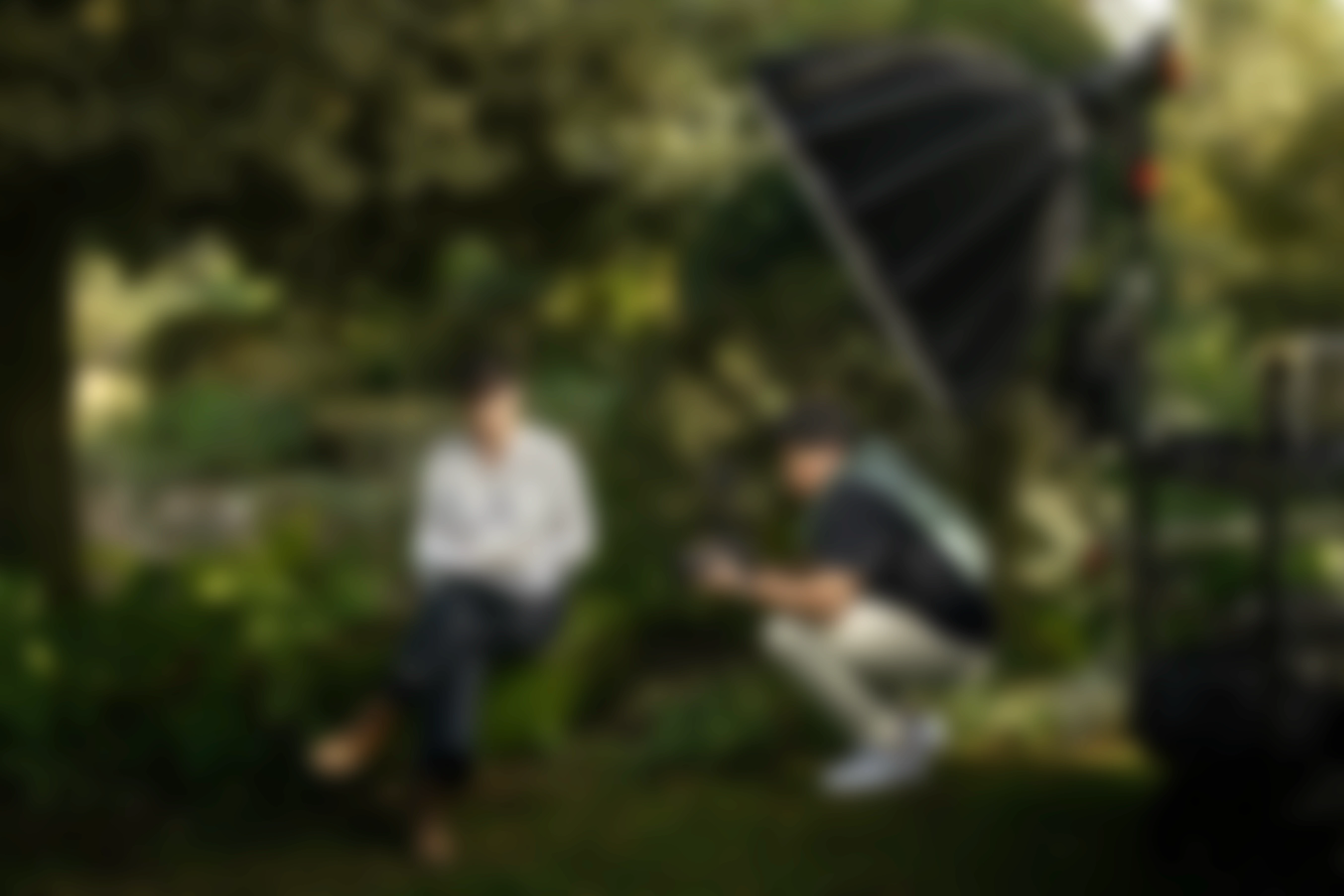 Person holding a green knitted handbag with a silver clasp, blurred green backdrop