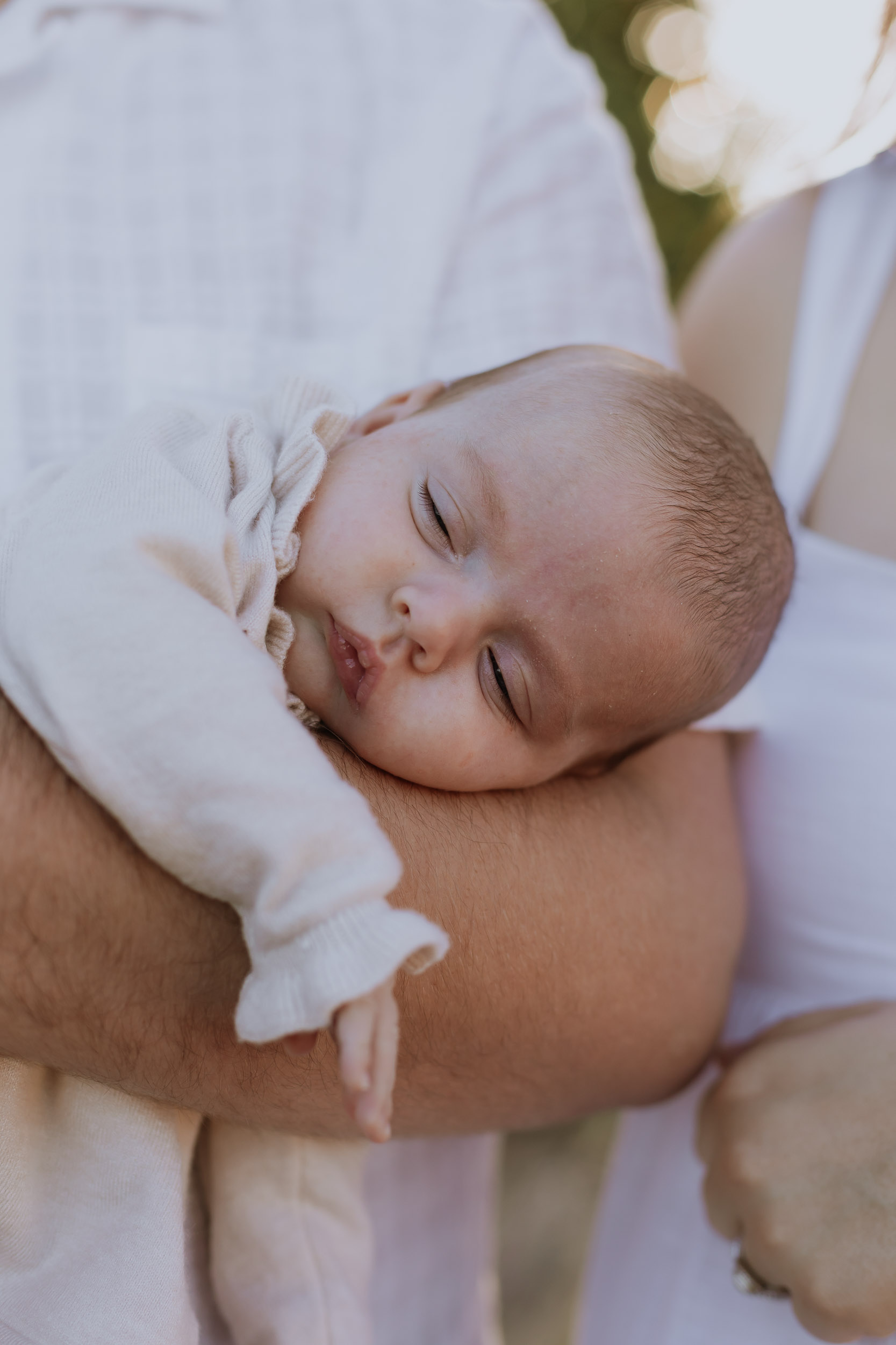 Newborn baby asleep on dad's arm during outdoor newborn photoshoot in Mackay
