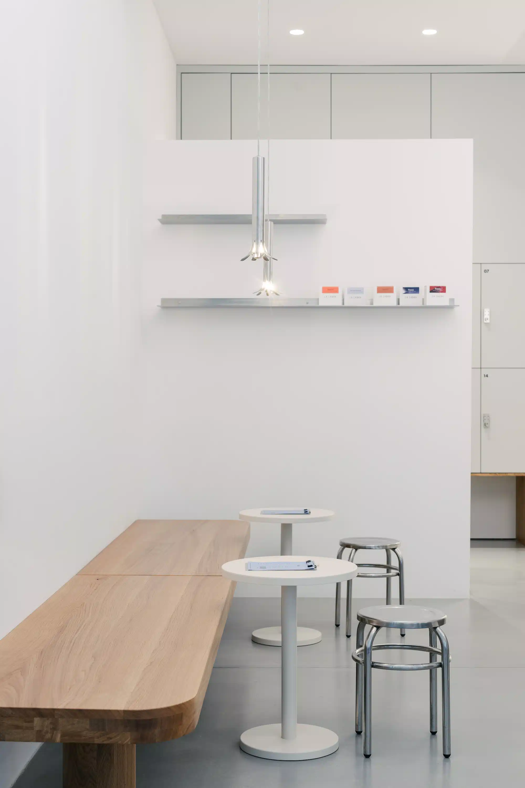 Reforma – minimalist seating area with wooden bench, white bistro tables and metal stools