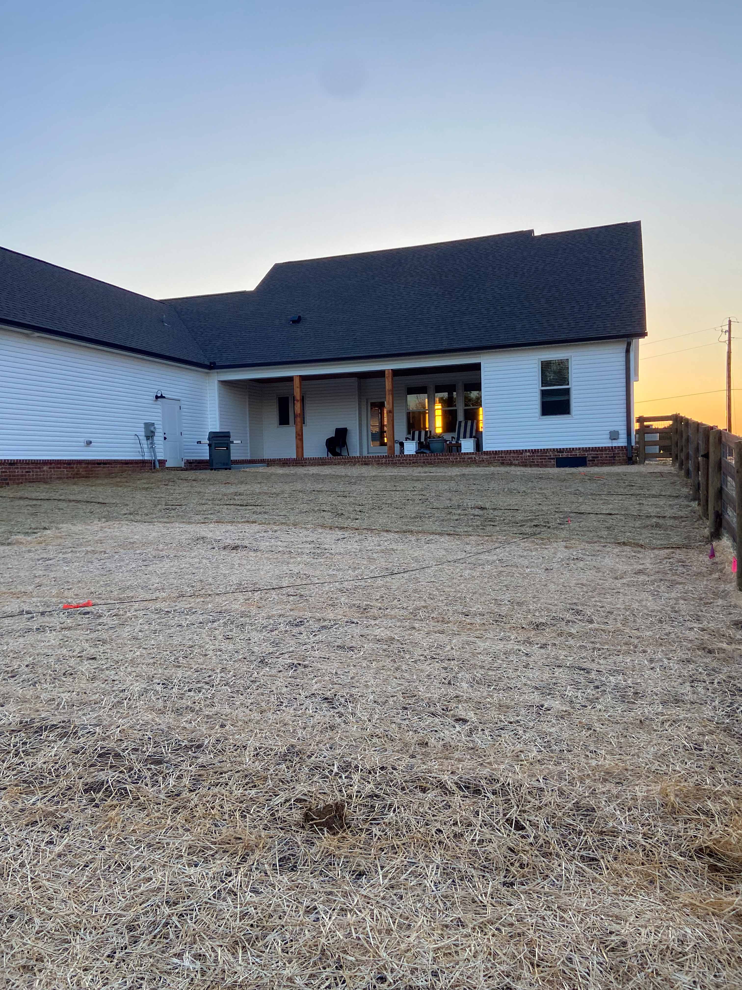 Open lawn area beside home with completed fencing