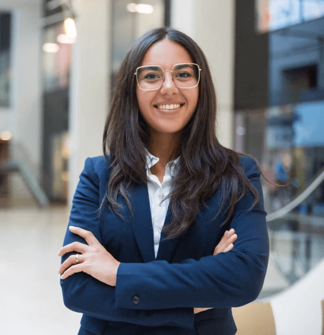 Woman with long brown hair turning to look over her shoulder on a city street.