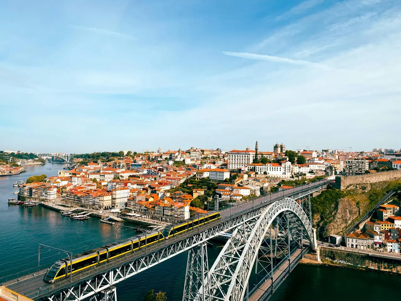 Aerial view of Porto: the Dom Luís I bridge over the Douro with a metro train crossing and the old town behind