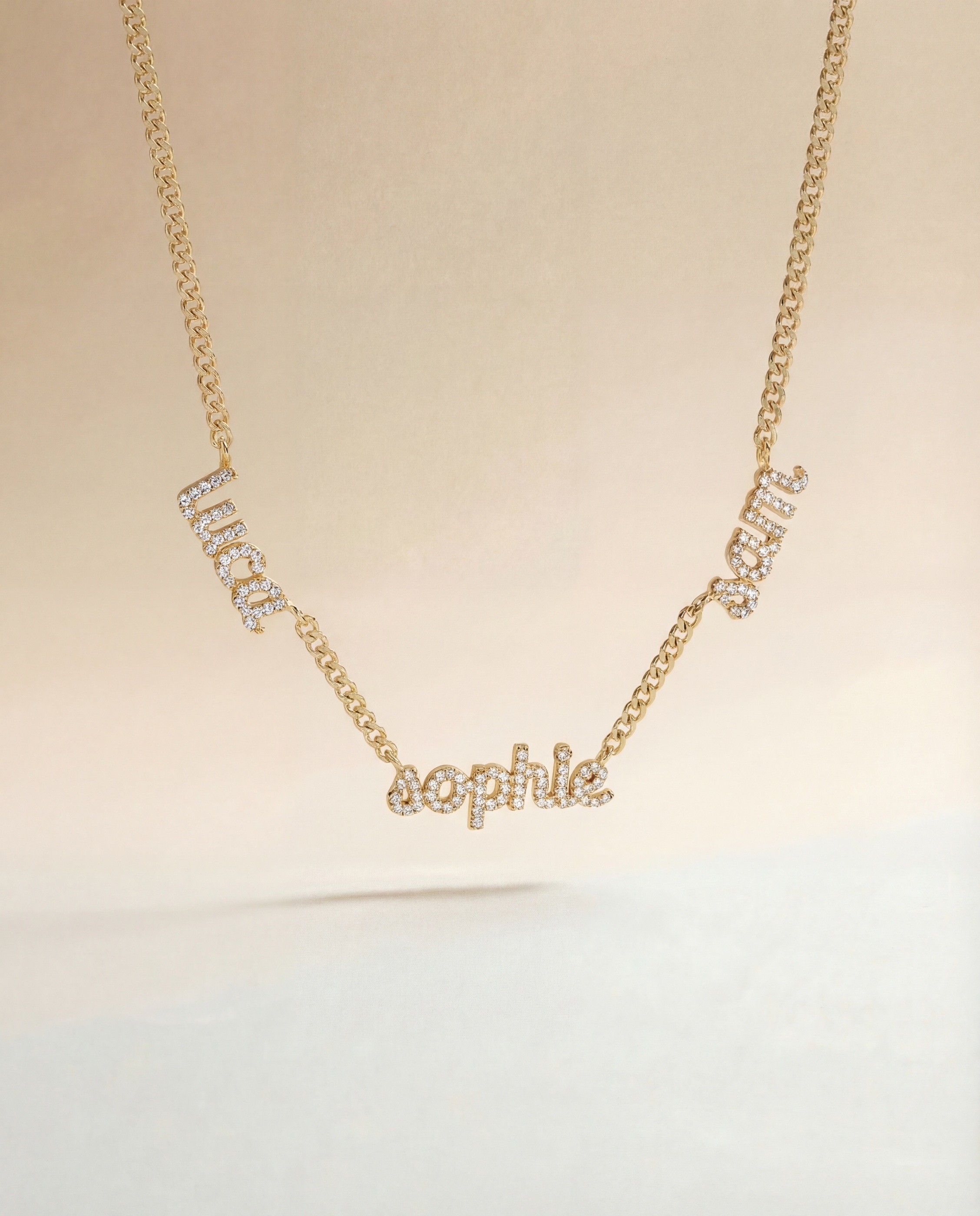 Vedder & Vedder — Personalized gold name necklace against a warm cream background.