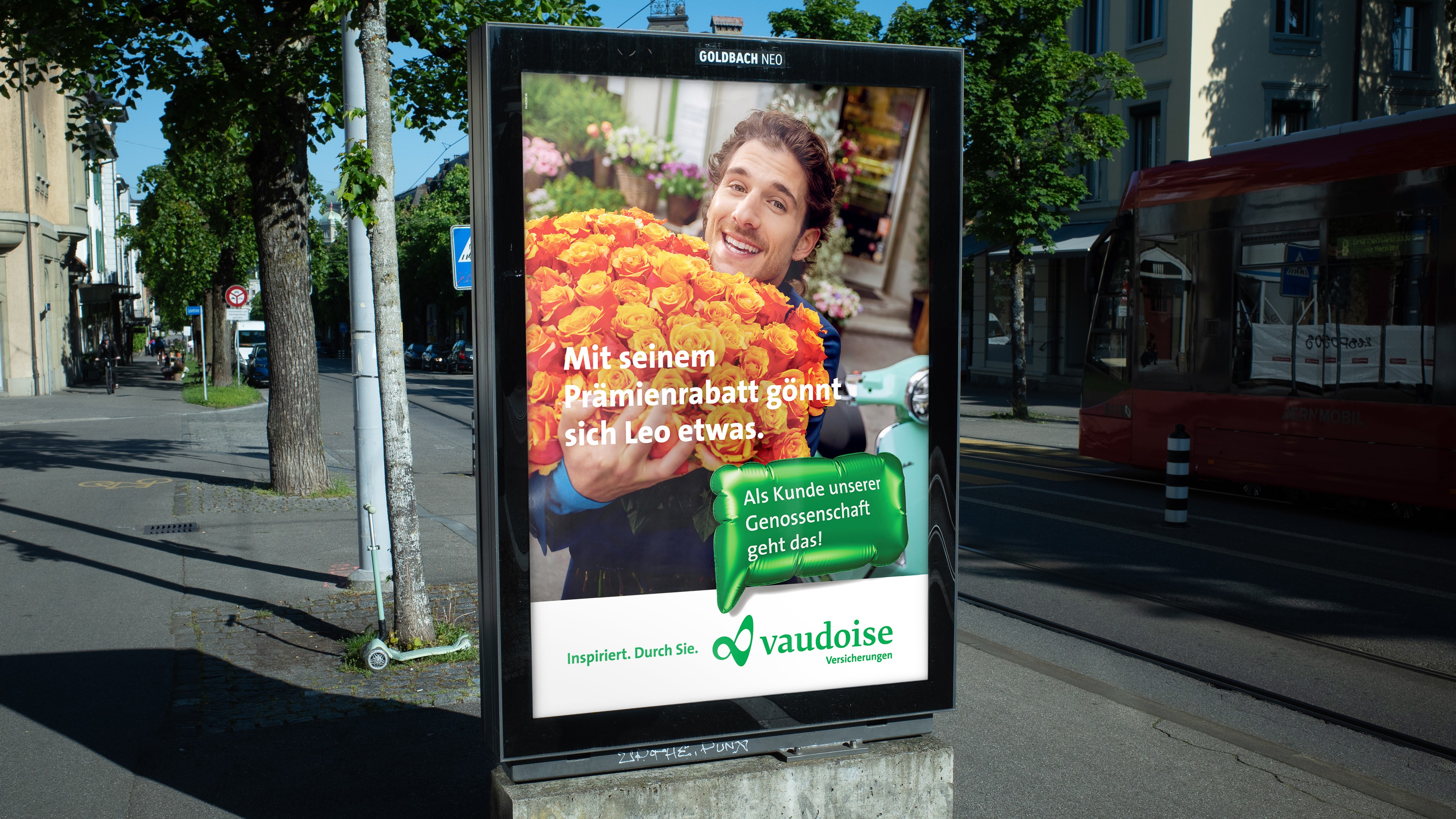 Billboard of a man with a huge flower bouquet, with German text about Vaudoise Versicherungen insurance discounts.