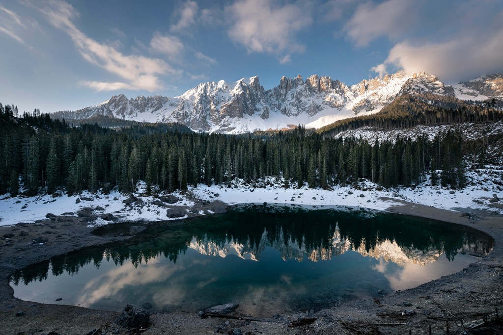 A lake surrounded by trees with a snowy mountain in the distance