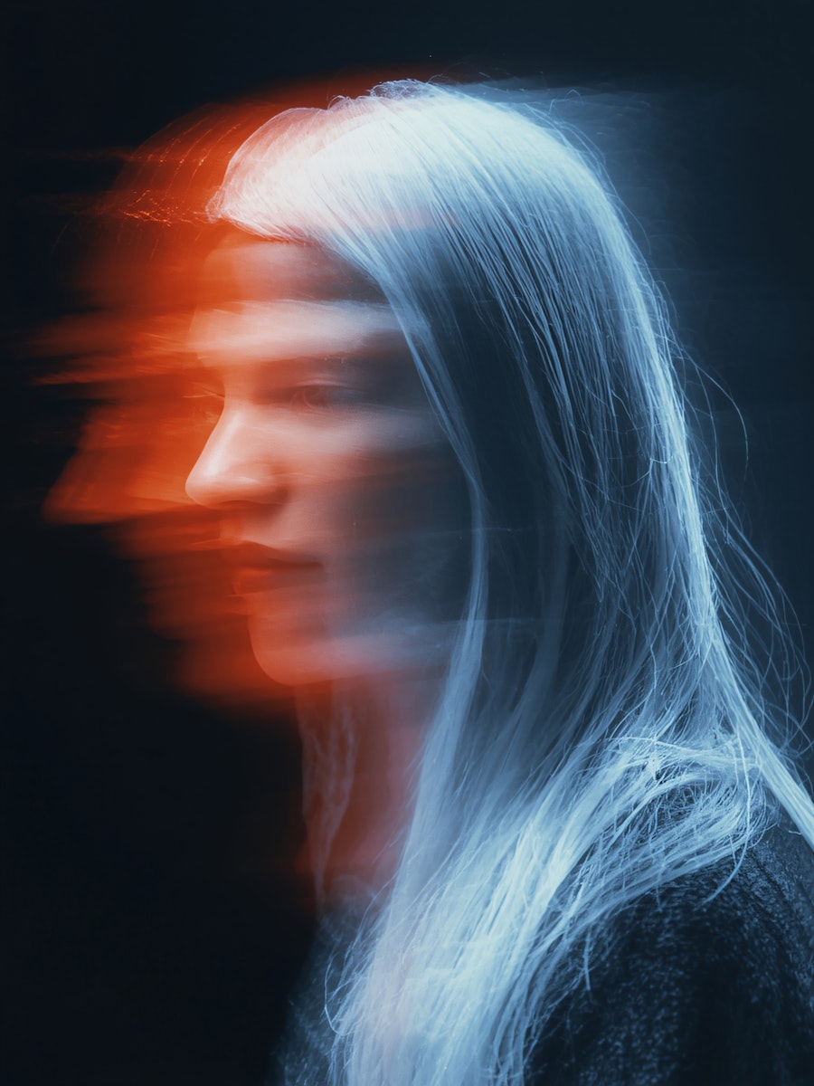 A blurred portrait of a person with long hair, creating a surreal and ethereal effect in cool tones.