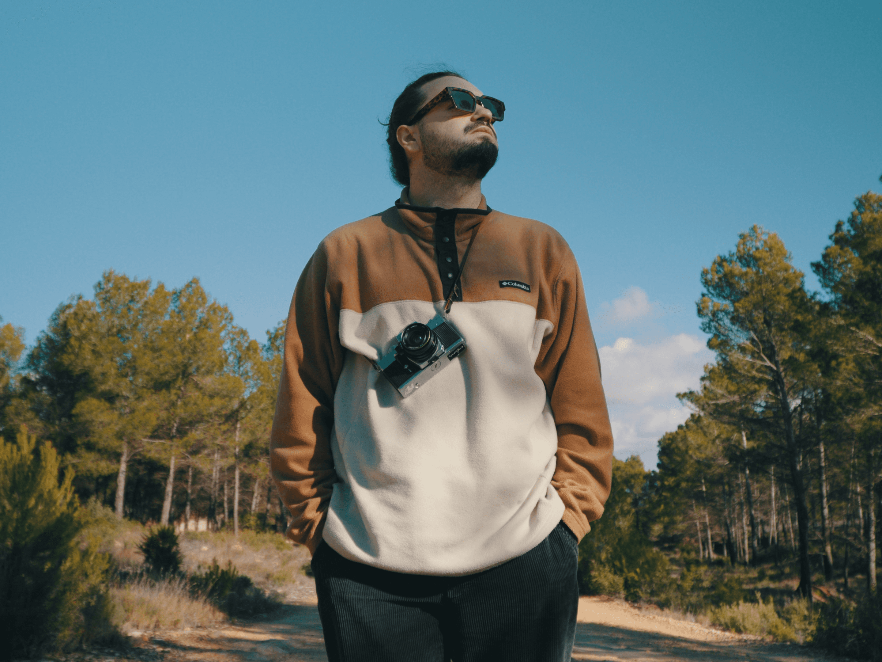 A person with wavy, shoulder-length hair wears a cream beanie and a matching thick-knit sweater over a gray shirt, giving a cozy, relaxed vibe.